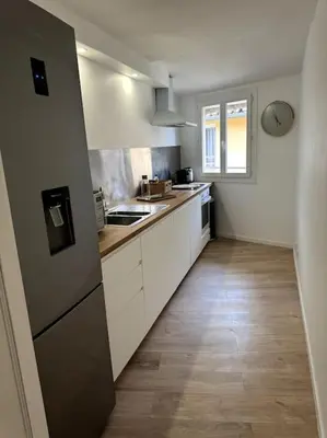 a kitchen with white cabinets and a wooden floor at Duplex rénové comme Neuf à Aix-en-Provence in Aix-en-Provence