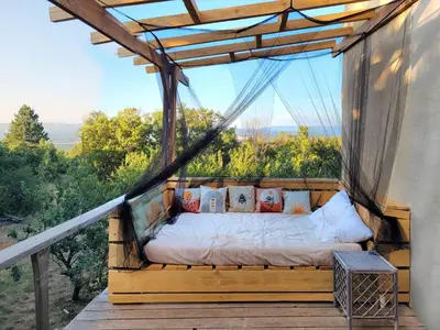 a bed on a balcony with a view of the mountains at Ecolieu Silenciane in Simiane-la-Rotonde