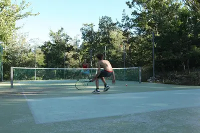 a man holding a tennis racket on a tennis court at Ecolieu Silenciane in Simiane-la-Rotonde