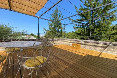 a patio with a table and chairs on a deck at Limasola - Apartment and its rooftop in Les Vignères