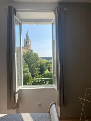 a window with a view of a church at Limasola - Apartment and its rooftop in Les Vignères