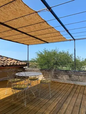 a patio with a table and chairs on a deck at Limasola - Apartment and its rooftop in Les Vignères