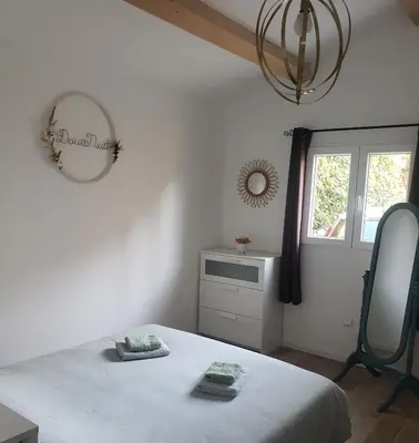 a bedroom with a bed and a mirror and a window at Maisonnette au cœur de Lauris in Lauris