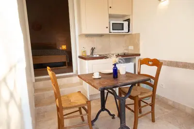 a small kitchen with a wooden table and chairs at Le gîte sous les pins in Les Taillades