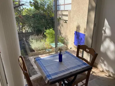 a table with a blue table cloth on it in front of a window at Le gîte sous les pins in Les Taillades
