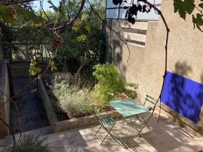 a blue chair sitting in a yard next to a wall at Le gîte sous les pins in Les Taillades