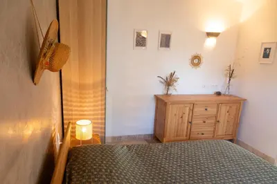 a bedroom with a bed and a wooden dresser at Le gîte sous les pins in Les Taillades