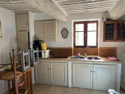 a kitchen with white cabinets and a sink and a window at La Magnanerie in Cabrières-dʼAvignon