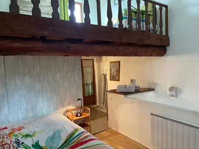 a room with a bed and a kitchen with a staircase at La Magnanerie in Cabrières-dʼAvignon