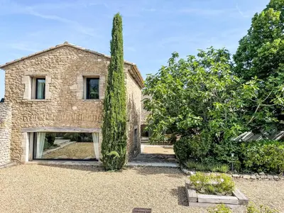 a stone house with a tall tree in front of it at Holiday Home Villa Montagne by Interhome in Oppède