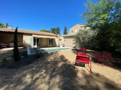 a yard with two red chairs and a house at Domaine Farandole in Eygalières