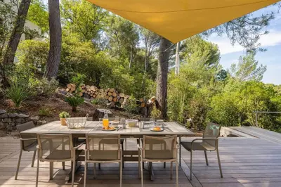 a wooden table and chairs on a deck with a table and chairsktop at Villa La Pinède in Aix-en-Provence