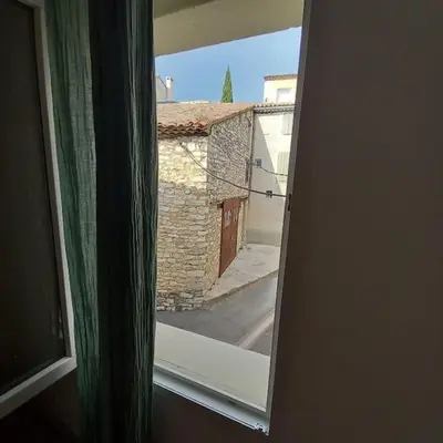 an open window with a view of a building at Le petit gîte de Rosalie in Blauvac
