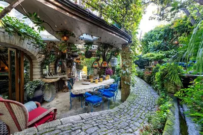 a stone patio with a table and blue chairs at La maison de la piscine in Goult