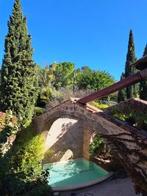 a stone bridge over a pond in a garden at Relais Tao in Rognes