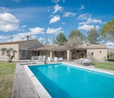 a group of benches on a deck under a tree at villa avec piscine à Gordes, en Provence in Gordes
