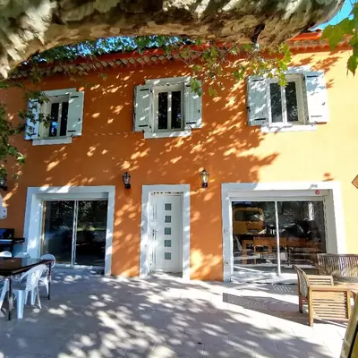 an orange building with tables and chairs in front of it at Maison Aix en Provence et grand jardin in Aix-en-Provence