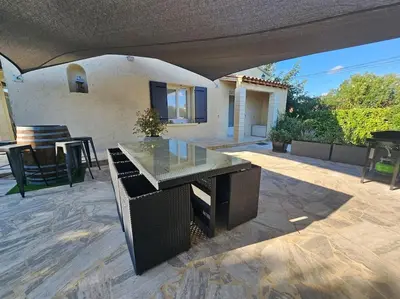 a patio with a glass table and a house at Paradise Corner in LʼIsle-sur-la-Sorgue