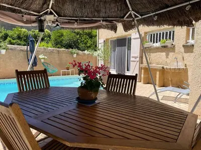 a wooden table with a vase of flowers on it at Grand studio avec piscine au coeur du village in Le Puy-Sainte-Réparade