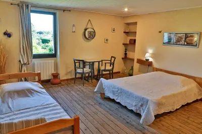 a bedroom with a bed and a table and chairs at sous la glycine de costebelle in Cheval-Blanc