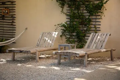 two wooden chairs sitting next to a wall at sous la glycine de costebelle in Cheval-Blanc