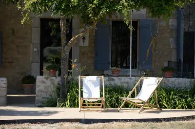 two chairs and a mirror in front of a house at sous la glycine de costebelle in Cheval-Blanc