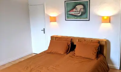 a bed in a room with two lamps on the wall at Chambre Voltaire ou Chambre Beckett, terrasse en bord de Sorgue in Le Thor