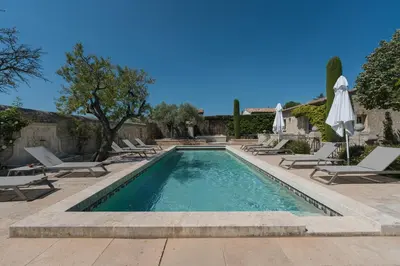 a swimming pool with lounge chairs and umbrellas at Mas Naste in Eygalières
