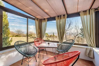 a room with four chairs and a table in front of windows at La Maison des Roches in Gordes