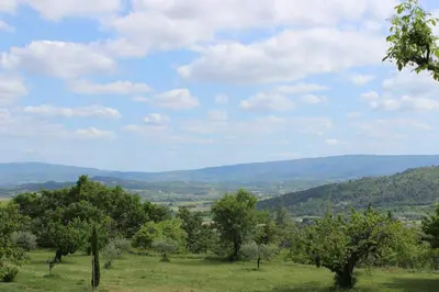 a field with trees and mountains in the distance at La Maison des Roches in Gordes