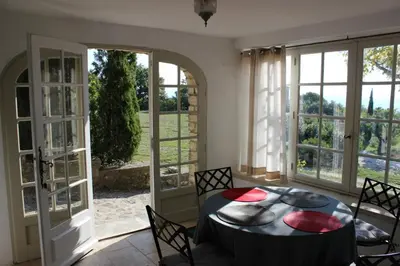 a dining room with a table and chairs and windows at La Maison des Roches in Gordes