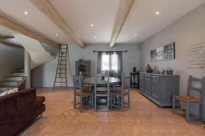 a living room with a table and a kitchen at Un Coin de Provence in LʼIsle-sur-la-Sorgue