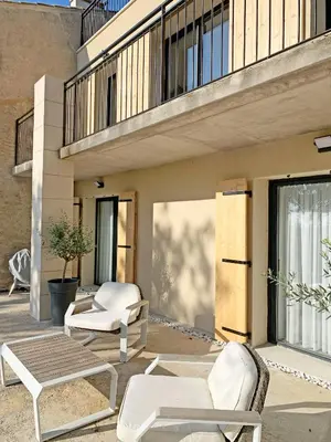 a patio with two white chairs and a table at Évasion Moderne en Provence in Lambesc