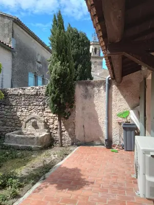 a courtyard with a tree and a stone wall at Maison de Village avec jardin dans Centre historique in Eyguières