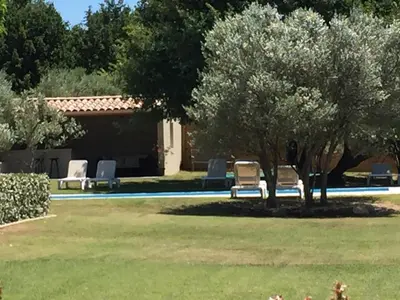 a pool with two lawn chairs and two trees at La Bastide au Ventoux in Bédoin