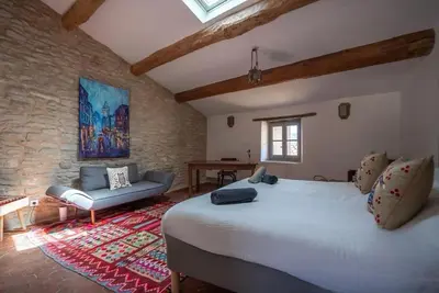 a bedroom with a large white bed and a couch at Grande maison de charme au coeur de Goult in Goult