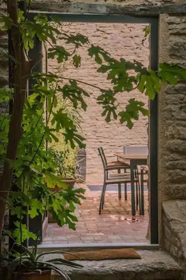 a patio with a table and a chair in a building at Grande maison de charme au coeur de Goult in Goult