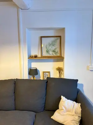 a living room with a gray couch with a pillow at La maison Haut-perché townhouse with view and jacuzzi in Saumane-de-Vaucluse