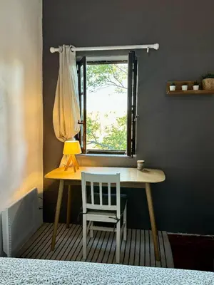a table with a lamp and a chair next to a window at La maison Haut-perché townhouse with view and jacuzzi in Saumane-de-Vaucluse