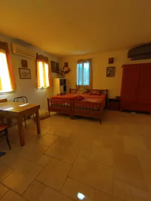 a bedroom with a bed and a table and windows at Luberon sud in La Bastidonne