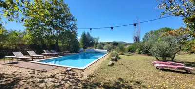 a swimming pool in a yard with chairs and a table at Une maison de famille dans le Luberon in Bonnieux