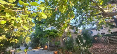 a yard with a house with a fence and trees at Une maison de famille dans le Luberon in Bonnieux