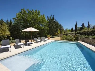 a swimming pool with chairs and an umbrella at Les Blayons - Exclusive Pool Villa Stunning View in Bonnieux