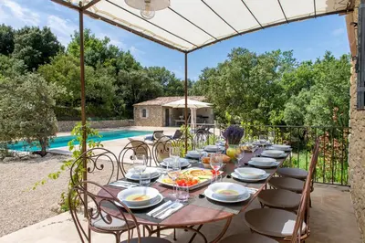a long table with plates of food on a patio at La Becasse Heritage Pool Manor in Bonnieux