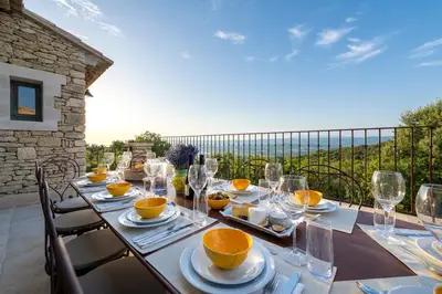 a long table with glasses and food on a balcony at La Becasse Heritage Pool Manor in Bonnieux