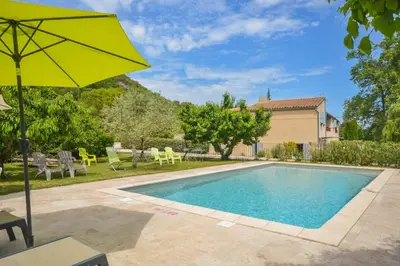 a pool with an umbrella and chairs and a house at Chambres d'hôtes 