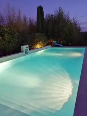 a large swimming pool at night with the lights on at Villa l'Hestia avec piscine à l'Isle-sur-Sorgue in LʼIsle-sur-la-Sorgue