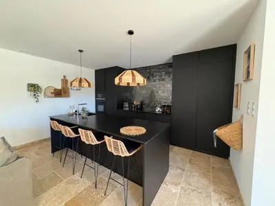 a kitchen with a black island with bar stools at Le petit Auzon in Mazan