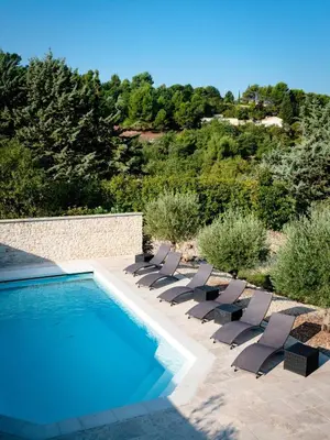 a group of lounge chairs and a swimming pool at La Petite Colline in Apt