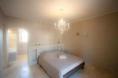 a bedroom with a white bed and a chandelier at La Collina De Rve in Apt